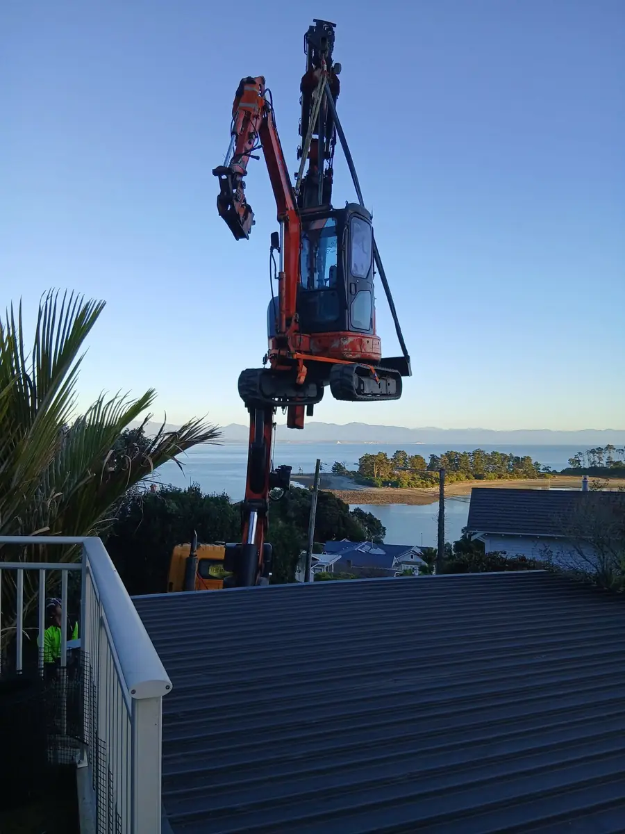 Crane lifting an excavator into a tight-access site