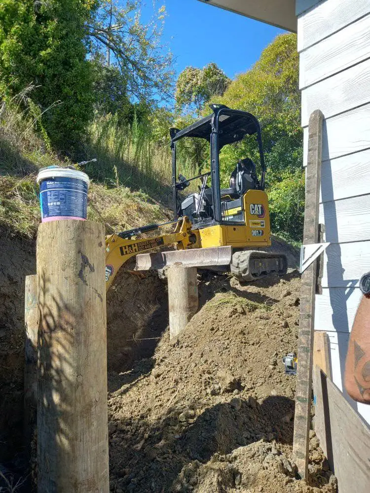 D&R Works excavator working a tight, steep site right against a house